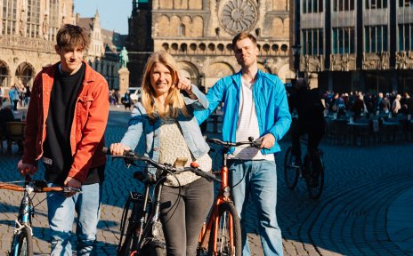 Junge Menschen schieben auf dem Bremer Marktplatz ihre Räder Junge Menschen schieben auf dem Bremer Marktplatz ihre Räder