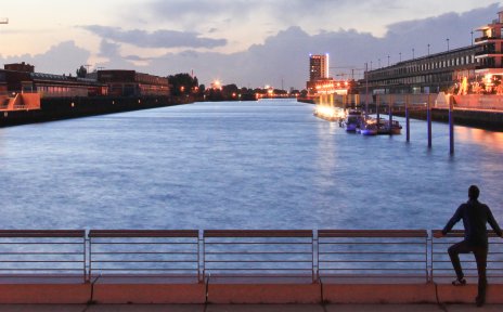 Ein Mann steht am Kopf des Hafenbeckens Europahafen und blickt auf den Sonnenuntergang Ein Mann steht am Kopf des Hafenbeckens Europahafen und blickt auf den Sonnenuntergang