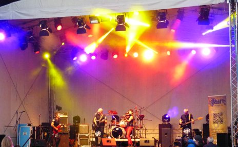 Eine Band steht auf einer großen und bunt beleuchteten Bühne. Eine Band steht auf einer großen und bunt beleuchteten Bühne.