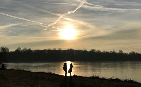 Ein Pärchen steht vor der tiefstehenden Wintersonne am gefrorenen Unisee Ein Pärchen steht vor der tiefstehenden Wintersonne am gefrorenen Unisee