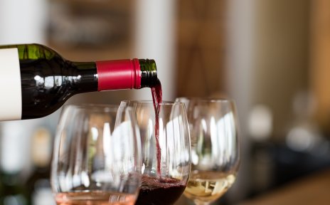 Drei gefüllte Weingläser, eine Flasche gießt Rotwein in eines der Gläser. Drei gefüllte Weingläser, eine Flasche gießt Rotwein in eines der Gläser.