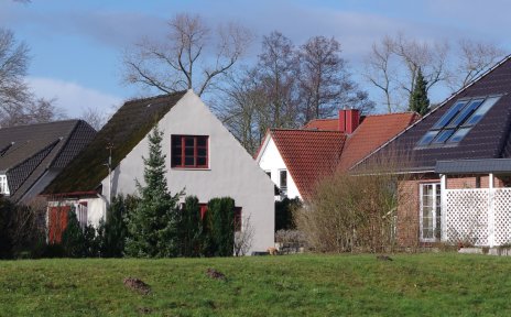 Freistehende Häuser hinter einem grünen Deich. Freistehende Häuser hinter einem grünen Deich.