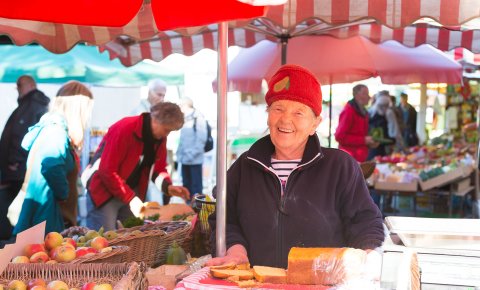Ein Verkäuferin an einem Marktstand lächelt in Richtung Kamera Ein Verkäuferin an einem Marktstand lächelt in Richtung Kamera