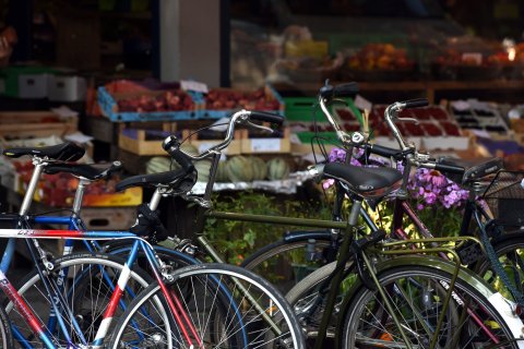 Parkende Fahrräder, im Hintergrund ein Obst- und Gemüsegeschäft mit Warenkörben vor dem Fenster. Parkende Fahrräder, im Hintergrund ein Obst- und Gemüsegeschäft mit Warenkörben vor dem Fenster.