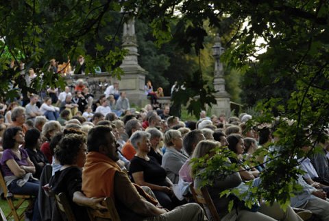 Menschen sitzen auf Stühlen in einem Park Menschen sitzen auf Stühlen in einem Park