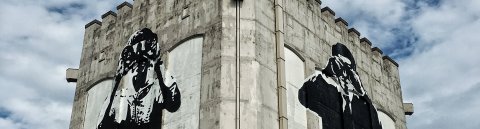 Streetart auf einem Bunker zeigt zwei menschliche Figuren mit Fernglas Streetart auf einem Bunker zeigt zwei menschliche Figuren mit Fernglas