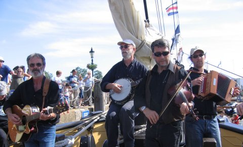 Ein Gruppe Musike vor einem Segelbot Ein Gruppe Musike vor einem Segelbot