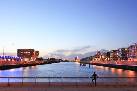 Ein Mann steht am Kopf des Hafenbeckens Europahafen und blickt auf den Sonnenuntergang Ein Mann steht am Kopf des Hafenbeckens Europahafen und blickt auf den Sonnenuntergang