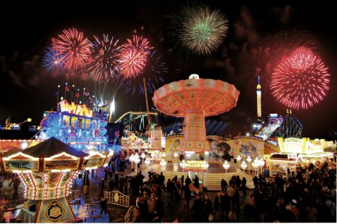 Beleuchtete Buden und Fahrgeschäfte auf dem abendlichen Bremer Freimarkt, darüber ein Feuerwerk Beleuchtete Buden und Fahrgeschäfte auf dem abendlichen Bremer Freimarkt, darüber ein Feuerwerk