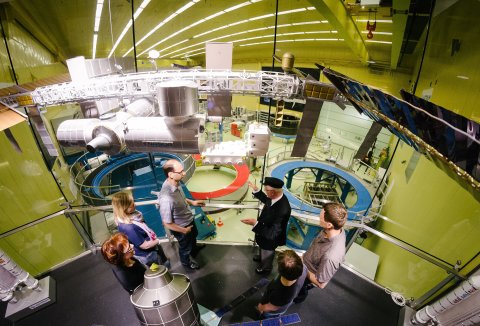 Eine Gruppe Besucher*innen wird durch Räumlichkeiten bei Airbus geführt. Eine Gruppe Besucher*innen wird durch Räumlichkeiten bei Airbus geführt.