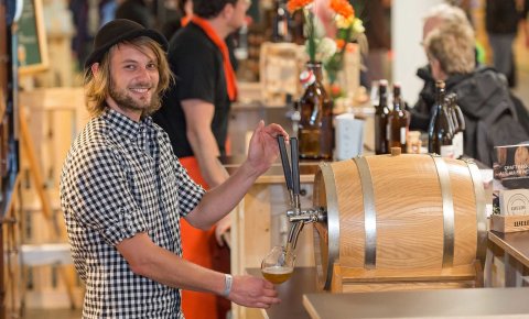 ein junger mann zapft bier beim craft beer event in der messe