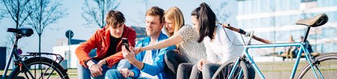 Vier junge Menschen sitzen auf einer Treppe, neben ihnen zwei Fahrräder Vier junge Menschen sitzen auf einer Treppe, neben ihnen zwei Fahrräder