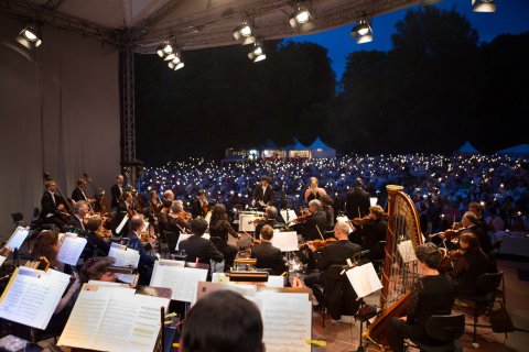 Ein spielendes Orchester vor einem Publikum, das Wunderkerzen in die Luft hält. Ein spielendes Orchester vor einem Publikum, das Wunderkerzen in die Luft hält.