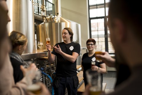 Ein Mitarbeiter und eine Mitarbeiterin der Union Brauerei führen eine Brauereiführung für Gäste durch. Ein Mitarbeiter und eine Mitarbeiterin der Union Brauerei führen eine Brauereiführung für Gäste durch.